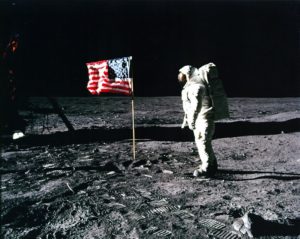 American flag planted on the moon with astronaut standing nearby
